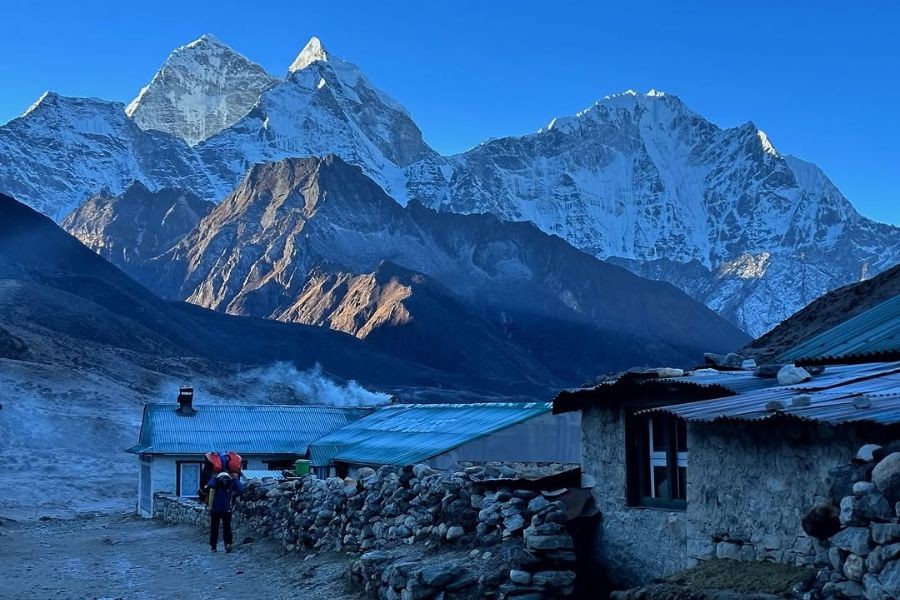 Stone teahouse buildings at dawn with snow-capped peaks behind